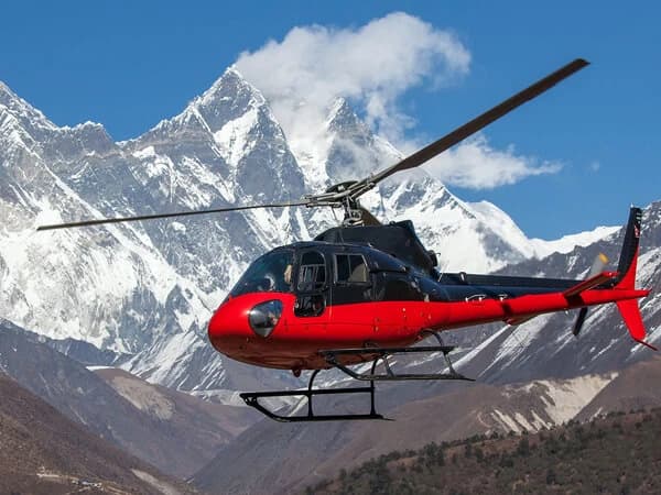 Helicopter flying above the Annapurna mountain range with a clear blue sky.